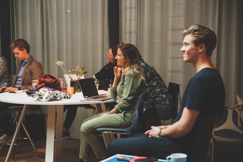 Employees listening to a colleague that holds a speech and all of them has a smile on their face