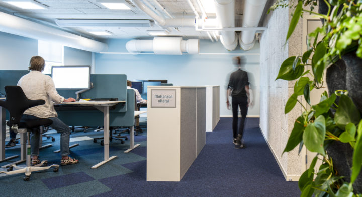 inside an office building. people working on their computers and someone is walking past